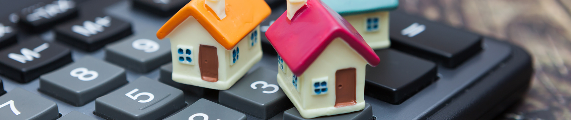 Hypotheek; drie kleine huisjes staan op een rekenmachine
